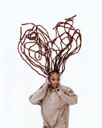 a woman with dreadlocks posing in front of a white background