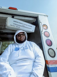 a man in a white hoodie sitting in the back of a truck