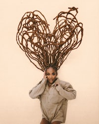 a woman with dreadlocks posing in front of a wall