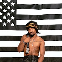 a man in leather pants standing in front of an american flag