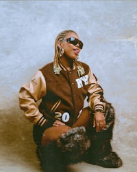 a woman in sunglasses and fur sitting on the ground