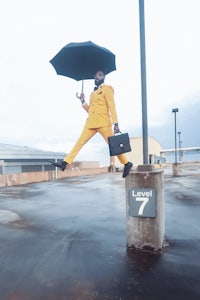 a man in a yellow suit jumping with an umbrella