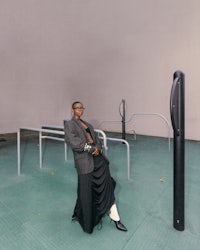 a woman in a long skirt standing next to a pole