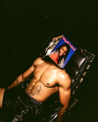 a man laying on a chair with a magazine on his head