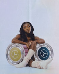 a black woman sitting on a mercedes wheel