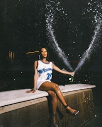 a woman sitting on a ledge with a bottle of champagne