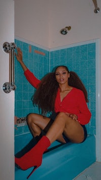 a woman sitting in a bathtub with red boots