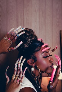 a woman is putting on a pair of pink fingernails