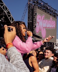 a woman singing in front of a crowd at a music festival