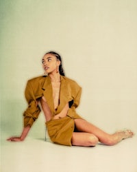 a woman in a tan jacket posing on the floor