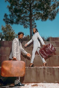 a man and woman walking down steps with suitcases
